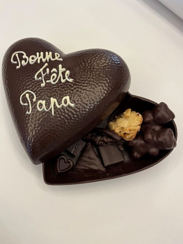 bonne fête papa sur un coeur en chocolat noir garni de chocolats assortis
